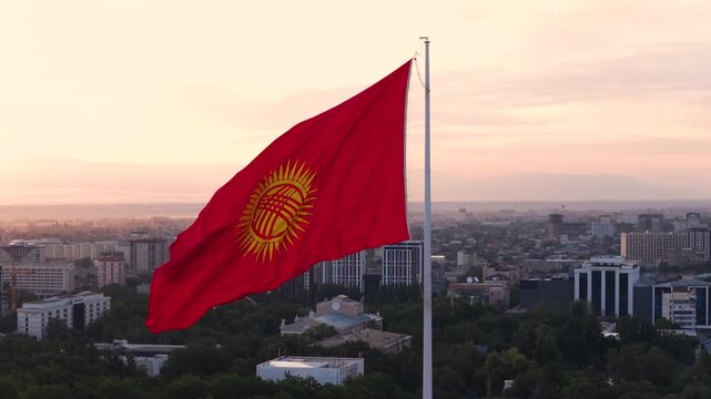 Closeup Of Kyrgyzstan Flag Waving With The Wind At Sunrise In Bishkek, Kyrgyzstan. - aerial shot