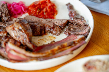Grilled beef steak, tomato sauce and fresh salad on a wooden table