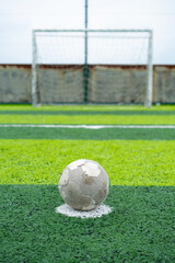 an old soccer on the penalty spot on a soccer field at vertical composition