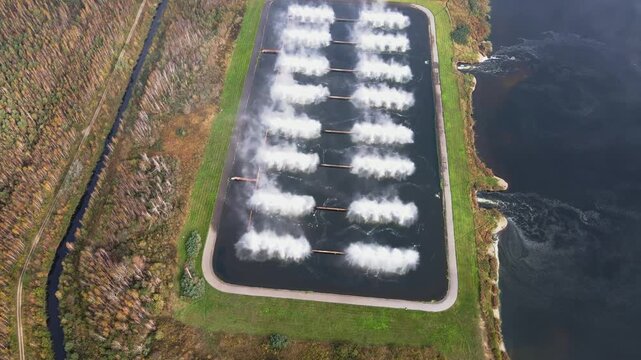 Aerial footage captures the structured spray ponds of Minsk TPP 5 near Minsk, Belarus, with basins, vegetation, and nearby water bodies in view.