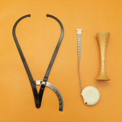 Black Obstetric Tazometer and measuring tape and obstetric wooden stethoscope on Orange Background,...