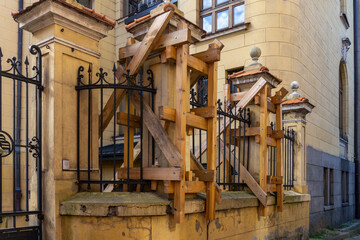 Historic tenement wall and fence reinforced with a wooden support structure, protecting damaged architectural elements from collapse.