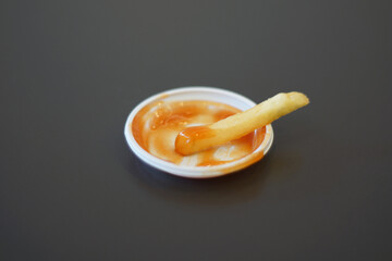 Last french fry dipped in the final trace of ketchup and mayonnaise, symbolizing the ending of a meal, simplicity, and satisfaction in fast food culture.