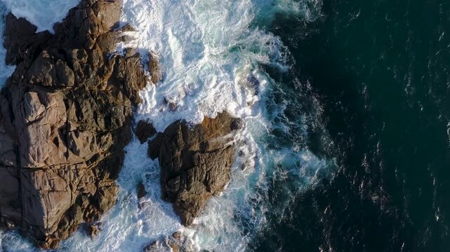 Aerial view of the ocean waves crashing against the rugged, rocky coastline, creating a dynamic interplay of textures and tones, Yallingup, Western Australia, Australia.