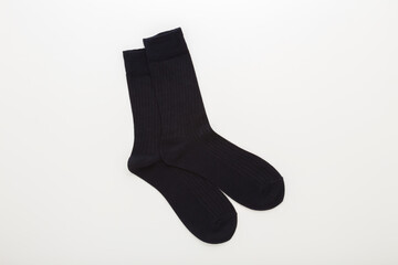Two new dark black long male socks on light gray table background. Closeup. Top down view.