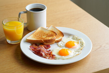 Breakfast plate with fried eggs bacon toast and orange juice