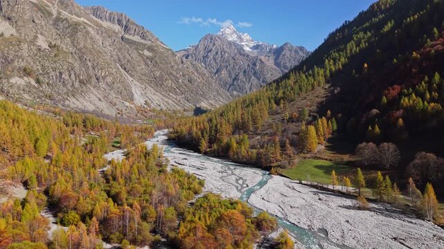 Aerial autumn view of Ecrins National Park in the Hautes-Alpes, French Alps. Champoleon Valley with Drac Blanc River, forest and Sirac alpine mountain peak. France