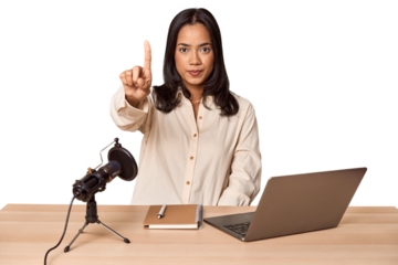 Woman records podcast with laptop showing number one with finger.