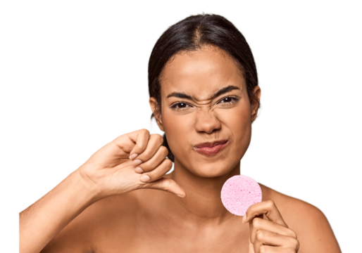 Woman holds facial sponge in studio showing a dislike gesture, thumbs down. Disagreement concept.