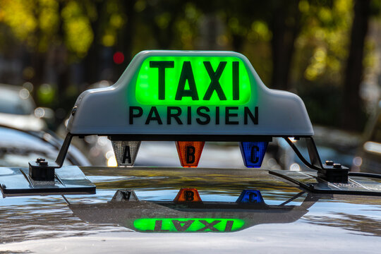 Gros plan du panneau lumineux sur le toit d'un taxi parisien avec le mot "TAXI" &eacute;clair&eacute; en vert (taxi libre) &agrave; une station de taxis, dans une rue de Paris, France