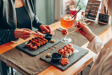 Friends Sharing Sushi Rolls with Cocktail in Restaurant