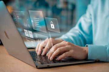 Close-up of skilled hands typing on a laptop with a futuristic holographic interface displaying security icons and data screens representing digital information processing and cybersecurity