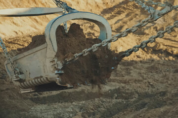 A dragliner bucket on cables scoops up soil at gold mine