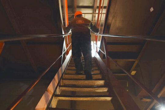 male crane operator climbs the ladder to the control cabin.