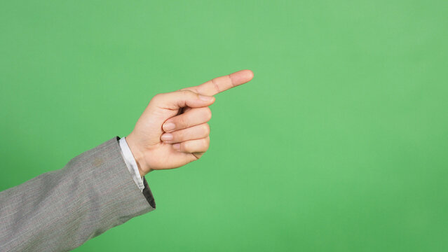 A hand in a gray suit and pointing with the index finger on green screen background.