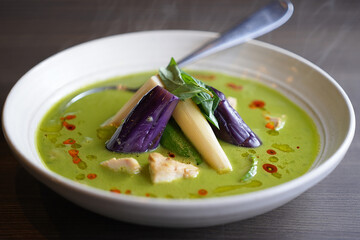 Delicious Thai green curry with chicken and eggplant in a white bowl