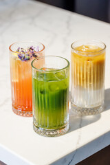 Assorted summer lemonades in glass jars with fresh fruits, ice, and garnishes