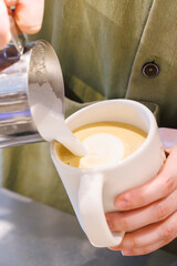 Barista crafting cappuccino with heart-shaped latte art