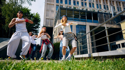 Street dance crew performing routine on city square with energy and confidence. Concept of dance and music, youth lifestyle, urban fashion, education events and creative social content.