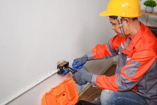 Electrician Repairing Electrical Wiring with Tools in a Residential Setting, Wearing Safety Gear and Helmet, Focus on Wiring and Tools