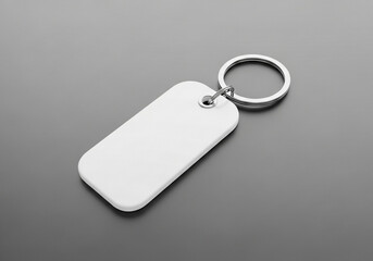 Fototapeta premium A white rectangular keychain with a metal ring on a gray surface in a studio setting view from above
