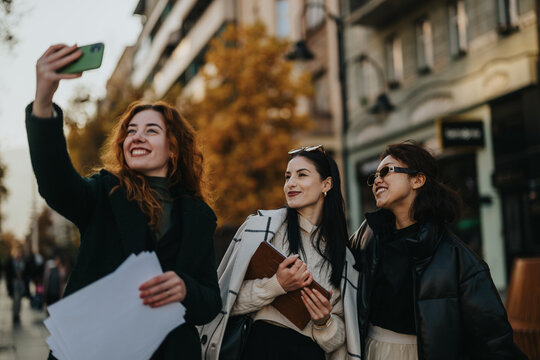 Young friends are taking a selfie on the streets during a sunny day, radiating positivity and enjoyment. They are engaging with one another, reflecting friendship and the happiness of being outdoors