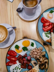 breakfast of fried eggs, sausages, beans, mushrooms and tomatoes accompanied by aromatic signature coffee