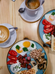 breakfast of fried eggs, sausages, beans, mushrooms and tomatoes accompanied by aromatic signature coffee