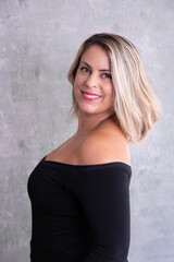 Fototapeta premium Selective focus sensual portrait of beautiful smiling blond young woman in off the shoulder black top