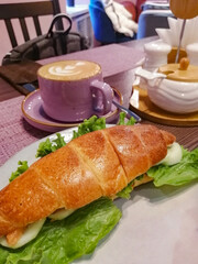 coffee mug with barista design with croissant on lettuce leaf bed