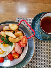 aromatic black tea in a clay mug and a delicious breakfast in a frying pan on a wooden table