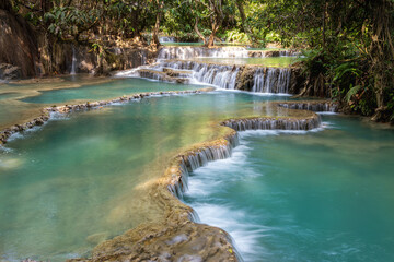 Kuang Si Waterfall flowing into a clear blue forest river in Luang Prabang, Laos