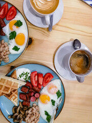 breakfast of fried eggs, sausages, beans, mushrooms and tomatoes accompanied by aromatic signature coffee