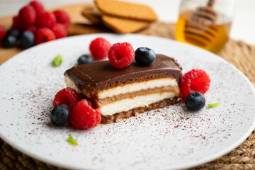Lotus cream and biscuit cake with a chocolate and red berry topping.