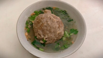 Hearty Indonesian Bakso Meatball Soup with Greens, a Delightful and Comforting Culinary Experience, Delicious Meatball Soup Garnished with Fresh Vegetables in a Rustic Bowl