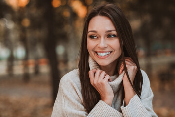 Cute woman enjoying an autumn day outdoors with a radiant smile and seasonal fall fashion in a colorful park setting