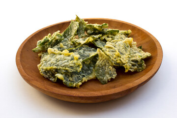 Chips made from spinach fried in flour on the wooden plate, isolated on white background.  A traditional snack from Indonesia.