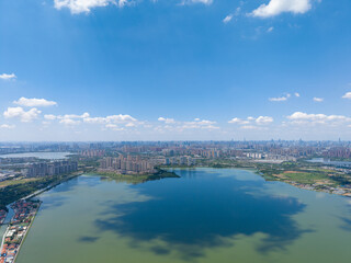 Fototapeta premium A beautiful aerial panorama of Tangxun Lake in Jiangxia District, Wuhan, China, showcases the sprawling urban landscape and calm waters under a bright blue sky.