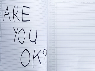 Concept of mental health support and awareness, with the question 'Are you ok?' handwritten in an open notebook with copy space
