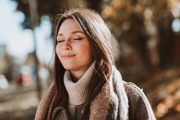 Young woman enjoys peaceful autumn day outdoors wearing a stylish coat and scarf, embracing the beauty of fall