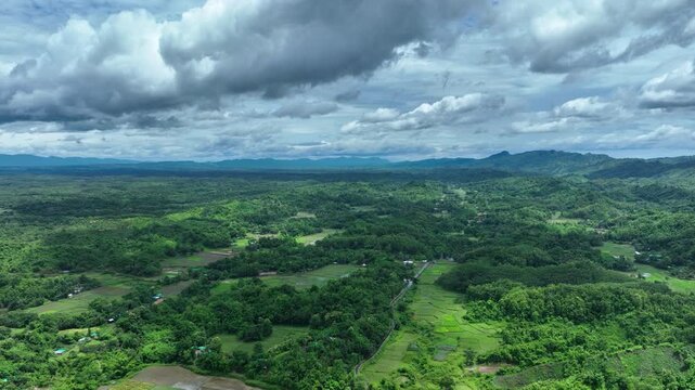 Aerial view of lush green hills, fields, and forests creating a vibrant tapestry under a cloudy sky, Ramu, Chittagong Division, Bangladesh.