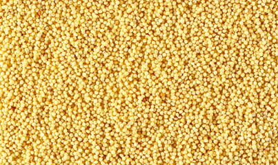Peeled, uncooked yellow millet seeds, organic food product background and texture