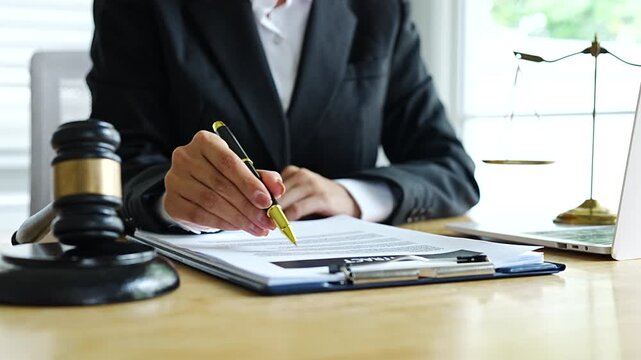 A lawyer reviews a contract document at a desk with a gavel, scales of justice, and a laptop, symbolizing law, legal advice, agreements, and professional consultation.