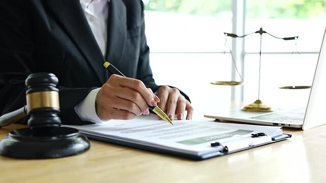 A lawyer reviews a contract document at a desk with a gavel, scales of justice, and a laptop, symbolizing law, legal advice, agreements, and professional consultation.