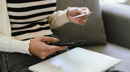 A young woman uses a laptop and credit card for online shopping, symbolizing modern finance, digital payments, e-commerce, banking, and technology-driven consumer lifestyles in today’s connected world