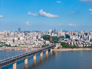 Fototapeta premium The vibrant city of Wuhan China stretches along the majestic Yangtze River, where a grand bridge connects bustling urban districts under a clear sky.
