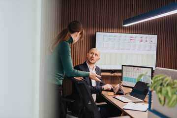 Business colleagues collaborating over data analysis in a professional workplace with technology, fostering teamwork and communication