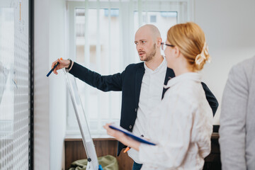 Colleagues brainstorming during an office meeting, using a whiteboard to enhance strategic discussions and teamwork.
