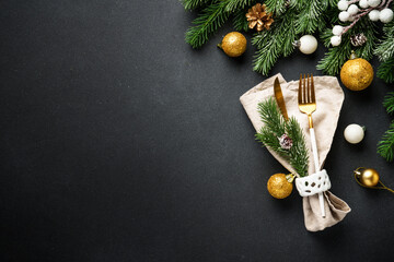 Golden cutlery and christmas decorations at black.