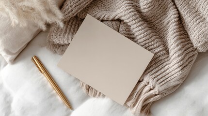 Blank beige card on white bedding, draped in tan knit